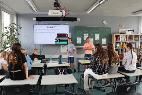 Schüler in einem Unterrichtsraum halten einen Vortrag über ILZ.