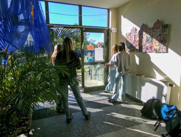 Kinder empfangen an der Schultür Gäste zum Tag der offenen Tür