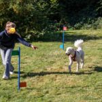 Schülerin mit Schulhund laufen im Schulgarten
