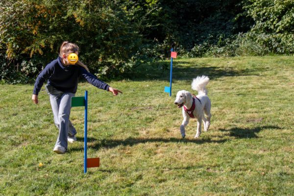 Schülerin mit Schulhund laufen im Schulgarten